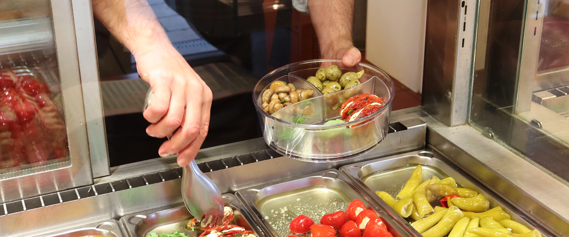 Antipasta werden in eine togo-Box gefüllt.